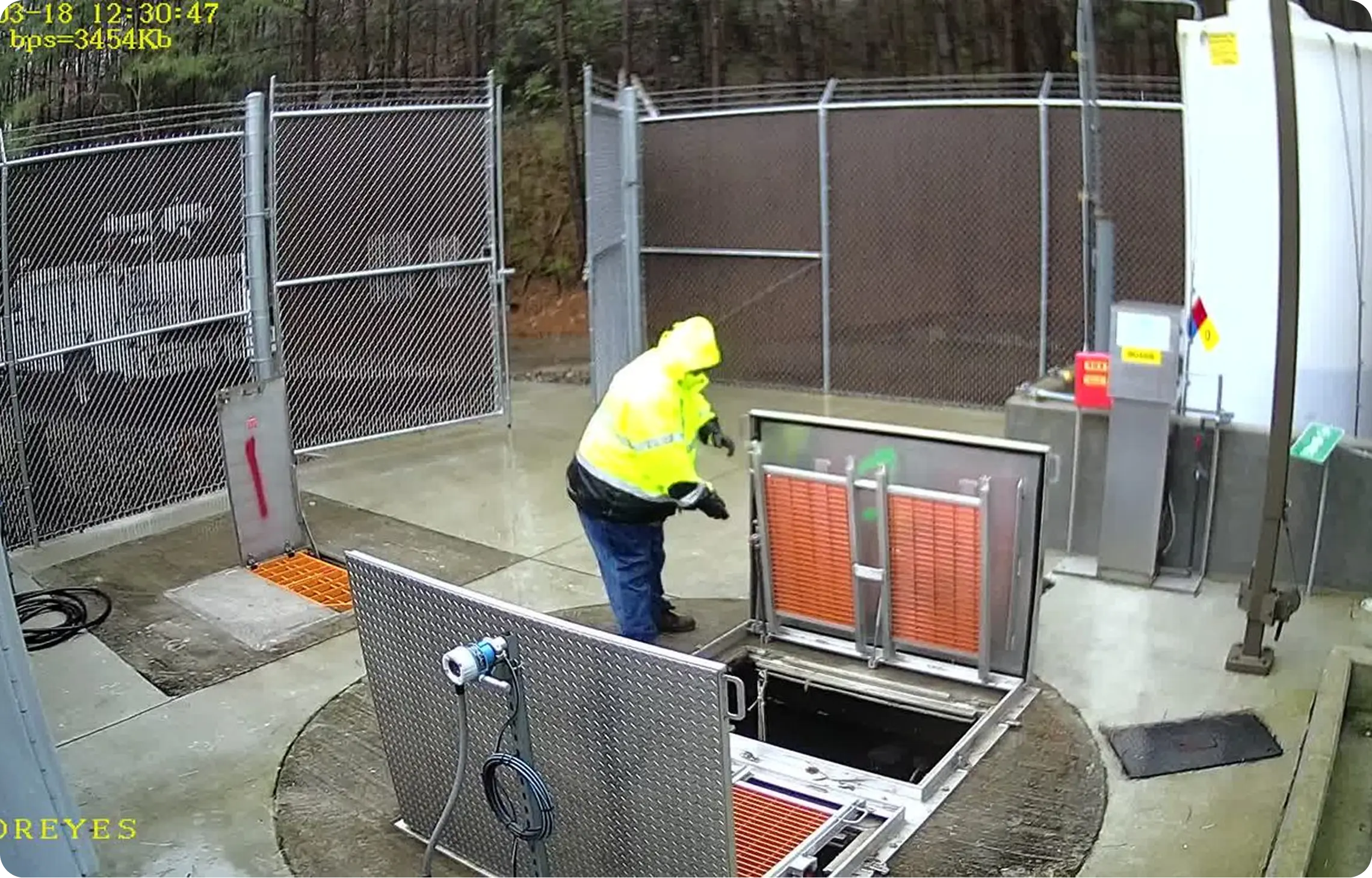 Memoreyes Municipal A person in a yellow safety vest is opening a metal box in a secure, outdoor, and