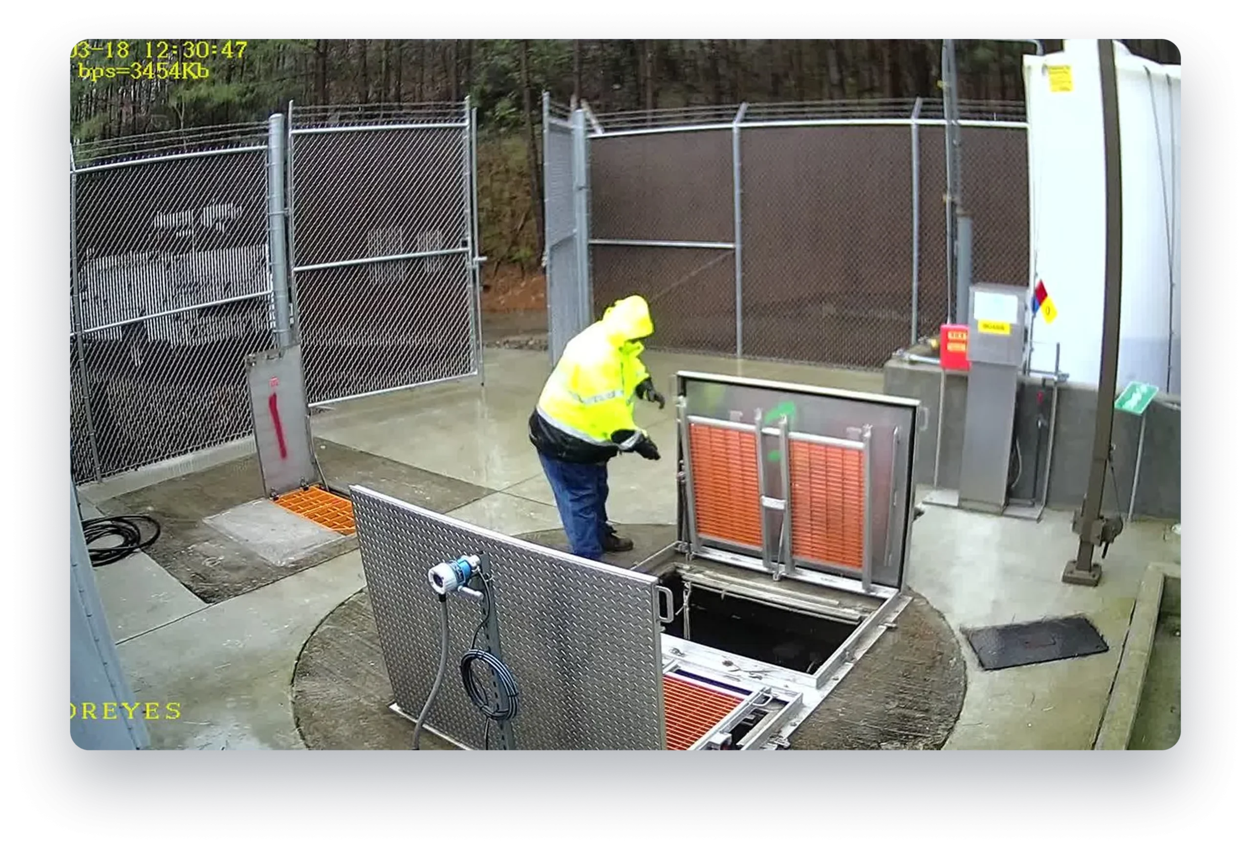 Memoreyes Municipal A person in a yellow safety vest and blue jeans is opening a metal door in a facility with a chain link